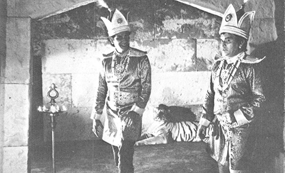 গুপী গান চালিয়ে যায়। পাশে বাঘা, পিছনে বাঘ।