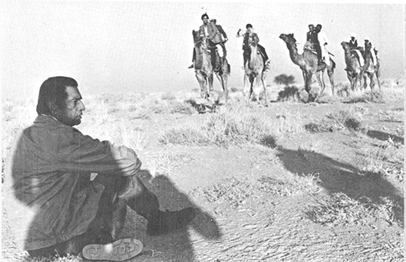 উট বনাম ট্রেন। ক্যামেরা আসার অপেক্ষায় পরিচালক। দূরে সকলে উটে চেপে প্রস্তুত।