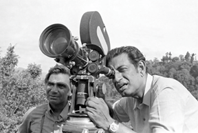 ক্যামেরায় চোখ রেখে, পাশে বন্ধু ও শিল্প-নির্দেশক বংশী চন্দ্রগুপ্ত‌